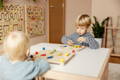 Two boys sitting on the table in kindergarten and playing with wooden Montessori toys.