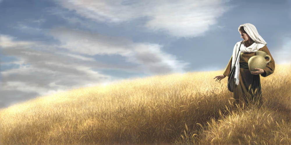 A woman stands in a full wheat field.