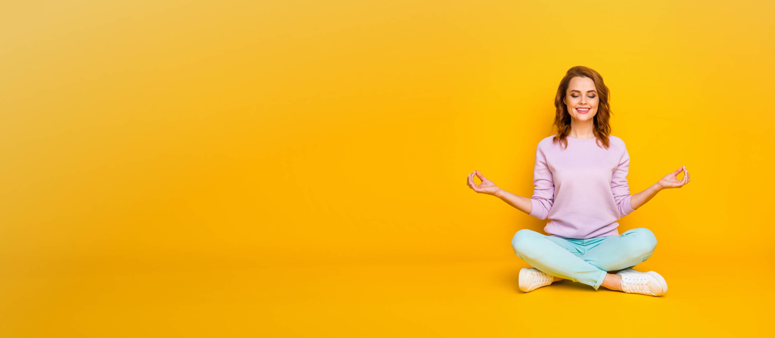 A smiling woman in a seated Sukhasana pose for Confetti's Virtual Yoga Class for Employees