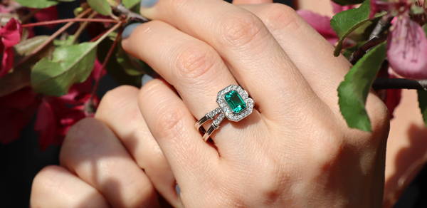 Sublime ladies' ring with an emerald surrounded by halo diamonds. Double ring body with diamond pavé.