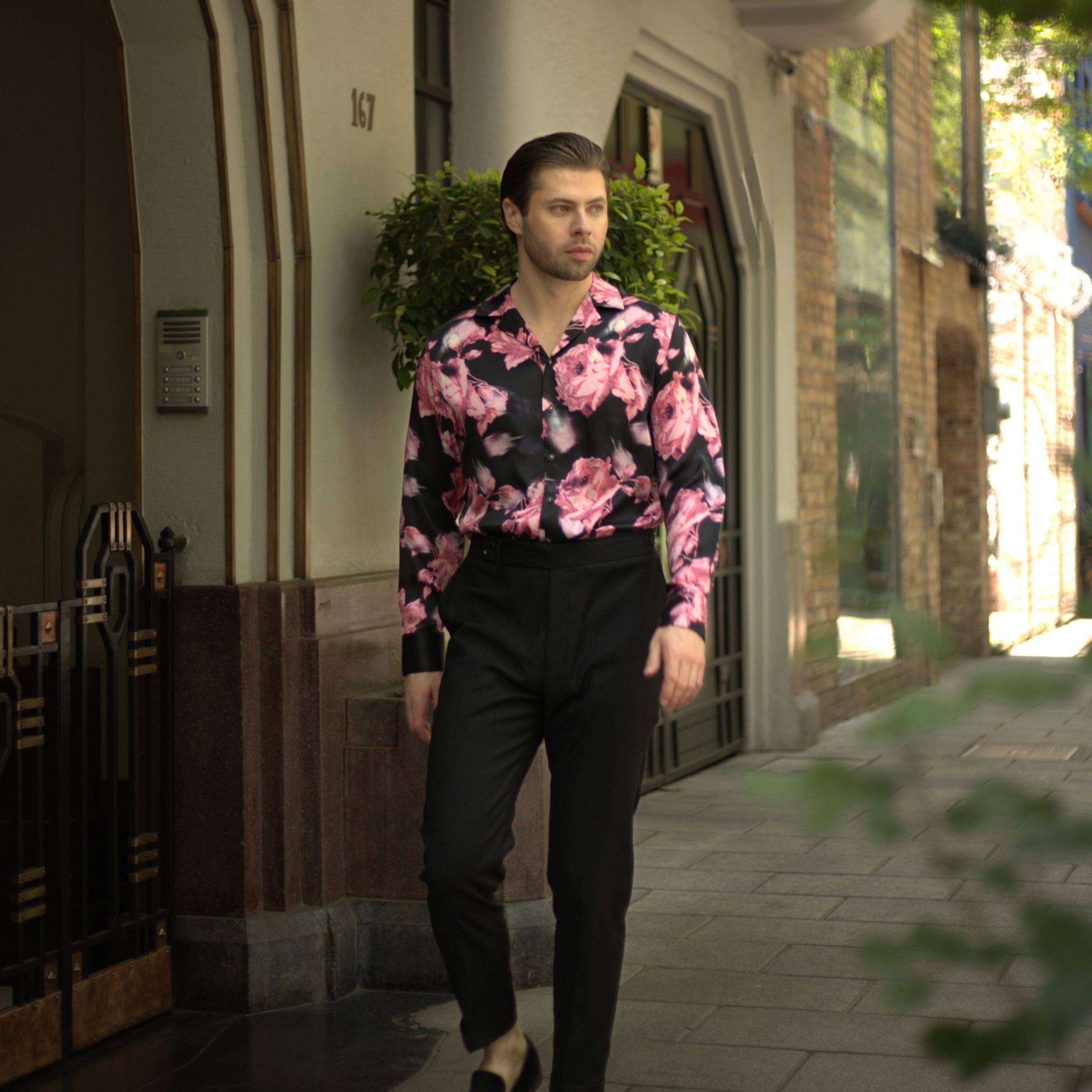 image of a model walking on the sidewalk wearing black pants and a black floral silk dress shirt from 1000 kingdoms