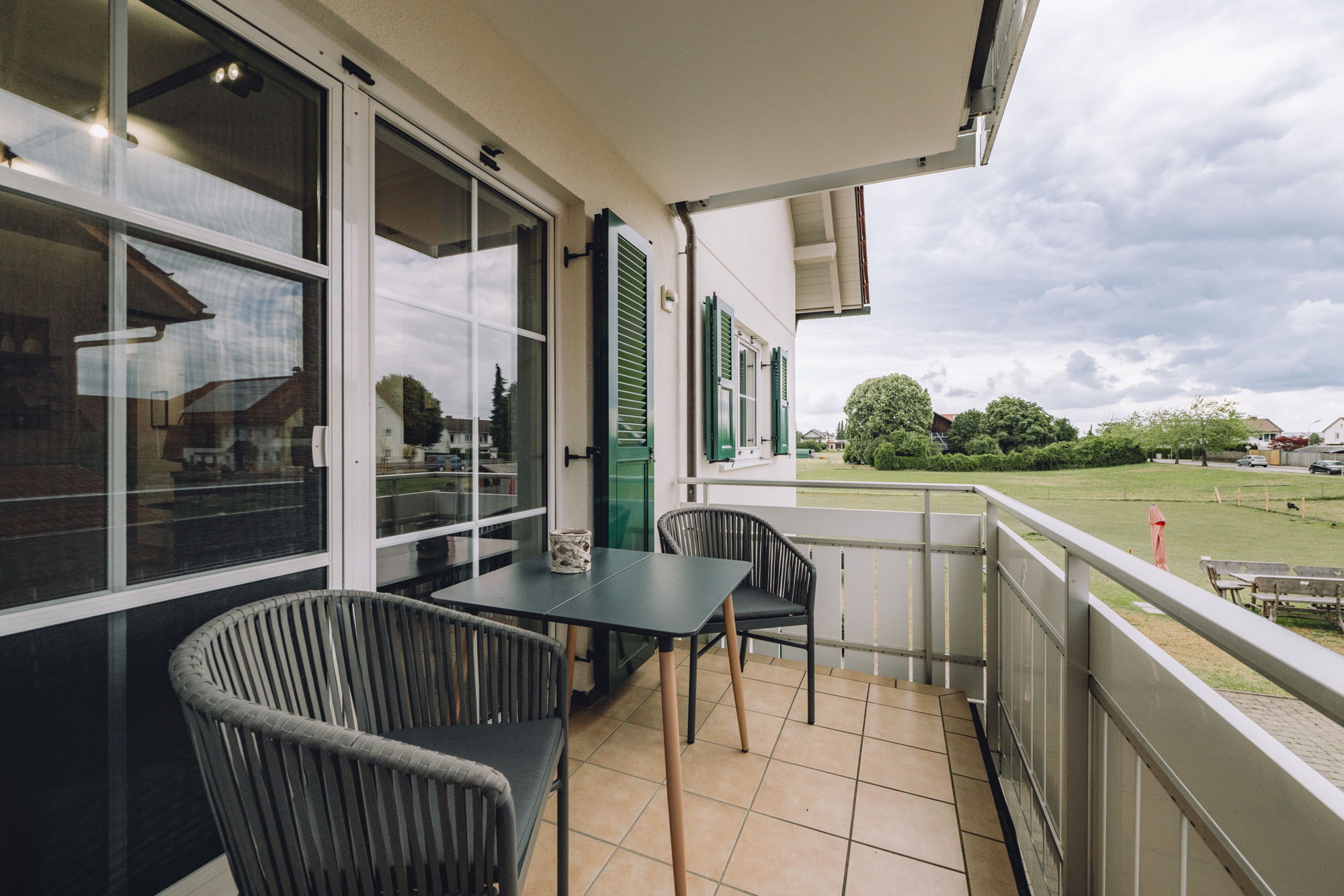 Ein Balkon mit Fliesen gepolsterten Stühlen und einem dunklen Tisch.