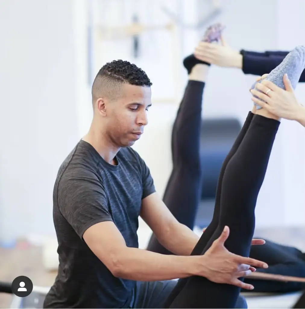 Photo of Brett Howard helping perfect a students form on reformer