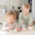 Cute sibling babies playing with Montessori Baby Stacking Cups.