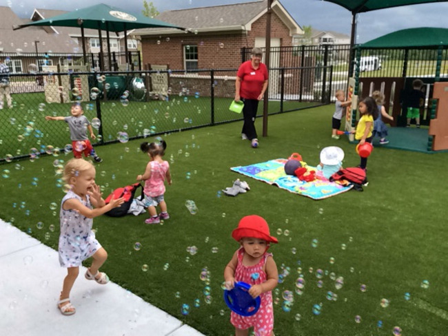 Primrose toddlers happily chase bubbles in the school yard