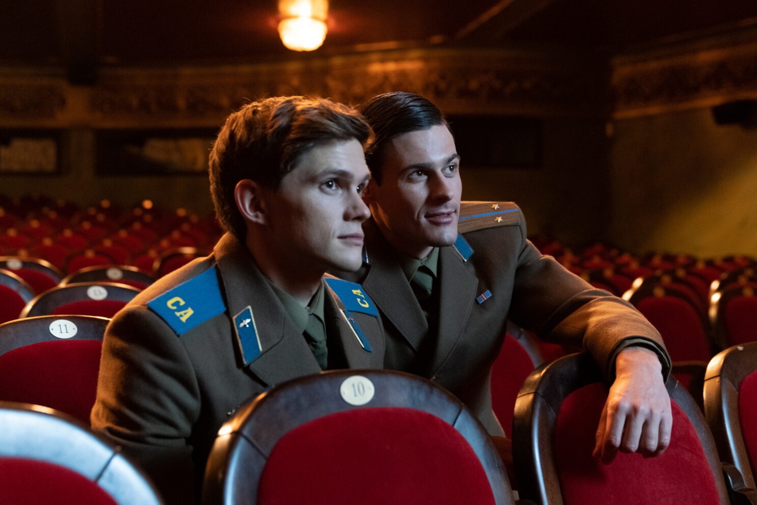 Sergey and Roman watching something at a cinema together sitting closely.