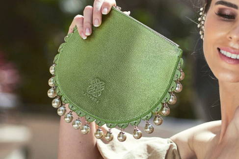 Close up, angled view of the CHARMAINE green leather clutch bag with tonal pearls.