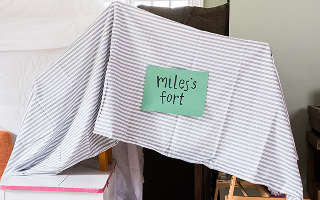 Indoor fort made out of bed sheets and chairs labelled "Miles's fort"