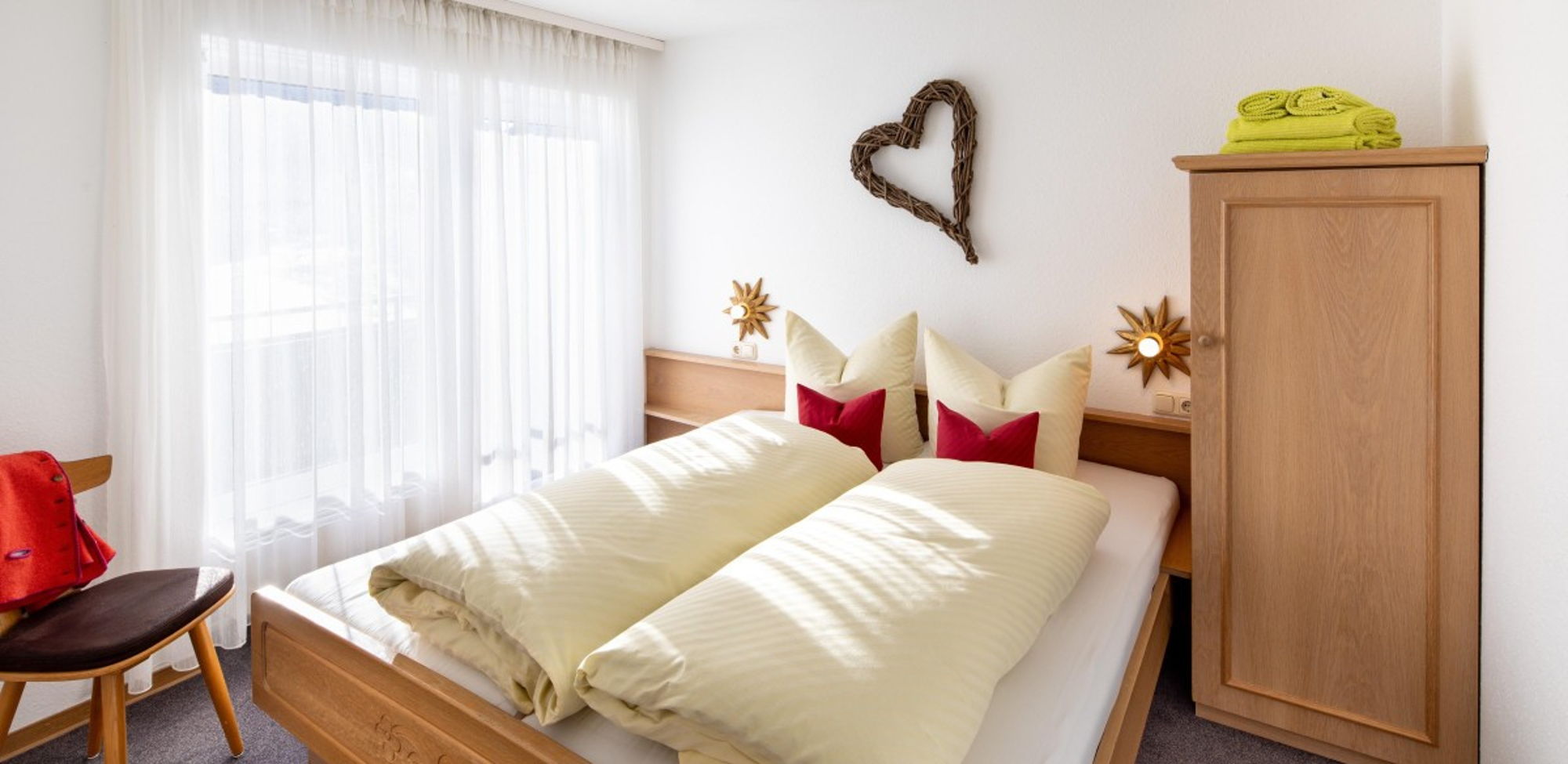 Doppelbett im geräumigen Schlafzimmer der 48m² Wohnung im Allgäu mit Blick auf die Berge