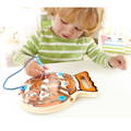 Little boy playing with the Montessori Fish shaped Magnetic Maze and moving the magnetic ball around it with a blue pen. 