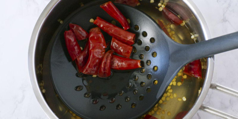 Using a strainer with bigger holes, scoop out the boiled dried chillies. The seeds will sink to the bottom of the pot.