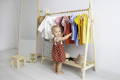 Montessori toddler choosing clothes from a low wooden clothing rack