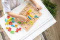 Boy playing with a wooden alphabet board and colorful wooden letters.