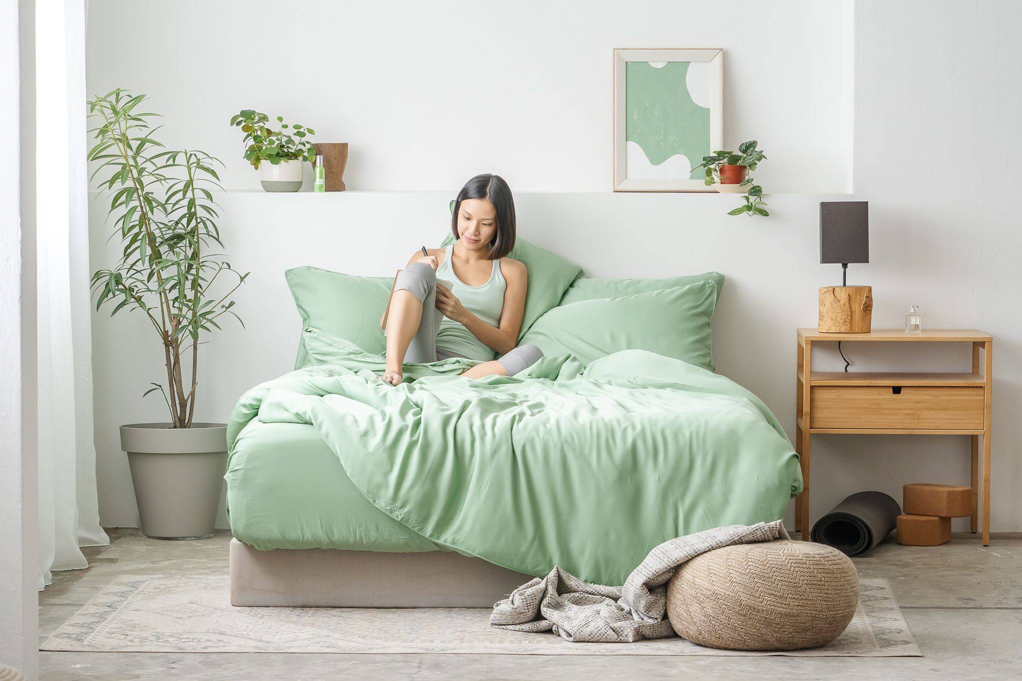 girl taking notes on bed featuring Weavve's Tencel Lyocell green bed sheets