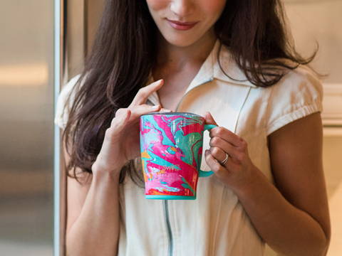 A woman holds a Swig coffee mug