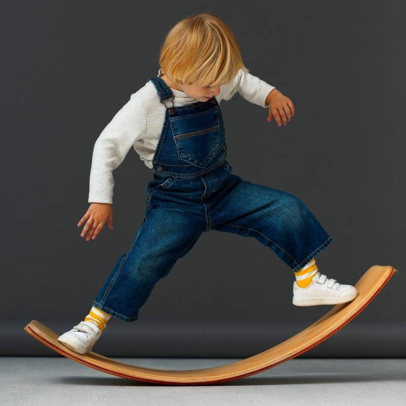 Child standing on a wooden balance board.
