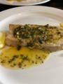 a piece of seabass with a butter sauce on a white plate