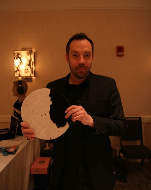 My Mooomat turntable cover in the hands of a salesmen at AXPONA 2014, where I purchased it.  Regardless of its efficacy, it goes well with the room decor, playing off the cowhide rug in front of the entertainment center.