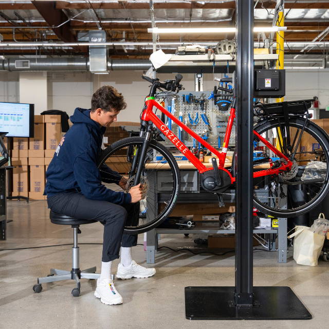 a mechanic servicing a red gazelle electric city bike