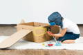 Boy making a DIY airplane out of cardboard and paint.
