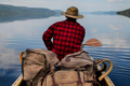 man sitting in the front of a canoe on a lake holding a paddle with three canoe backs behind him