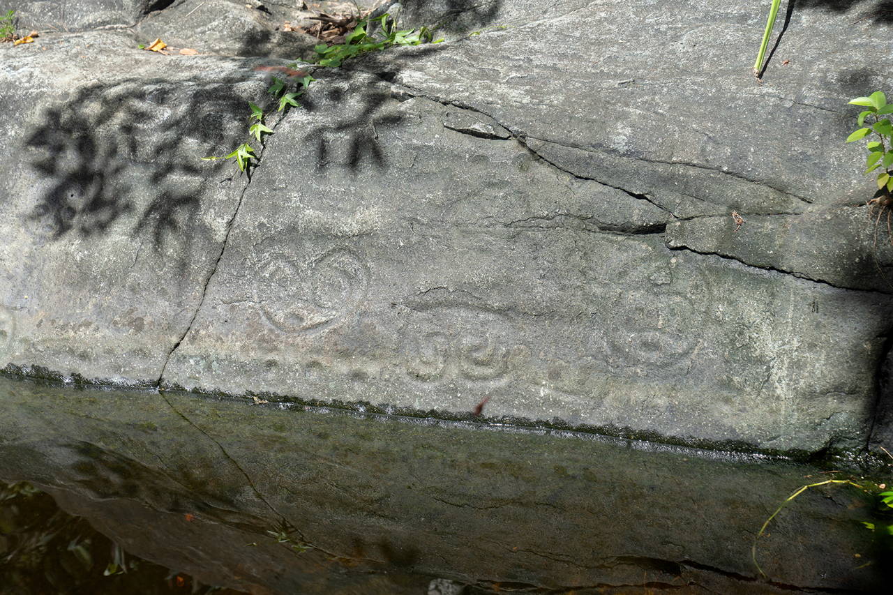 The petroglyph symbols on the rock reflecting into the freshwater pond.