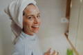 woman smiling with a purifying face mask on her face