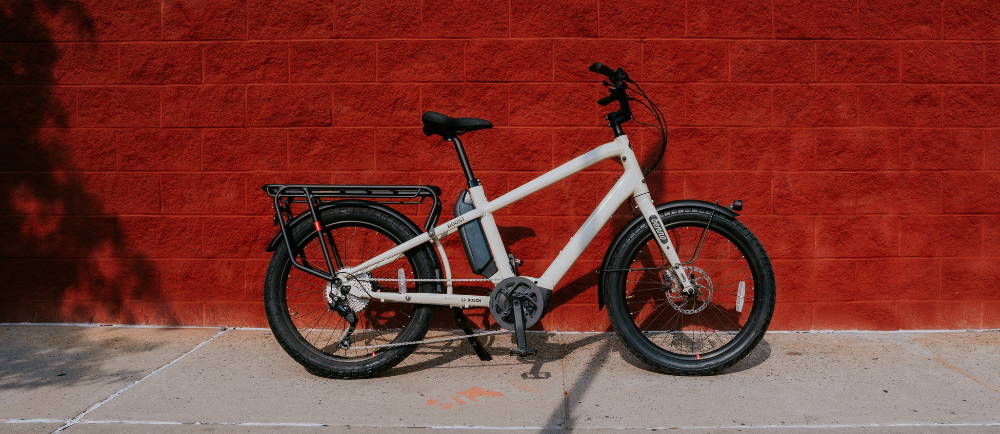 a white cargo bike in front of a red brick wall