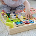 Baby touching a slider on the wooden Montessori Busy Dashboard toy.