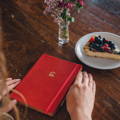 A bright red Artebene notebook with gold embossed cherry on the cover