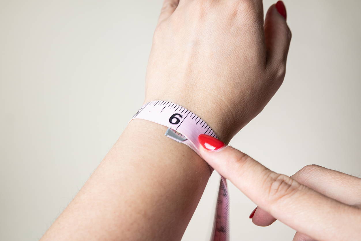 A woman measuring her bracelet size.