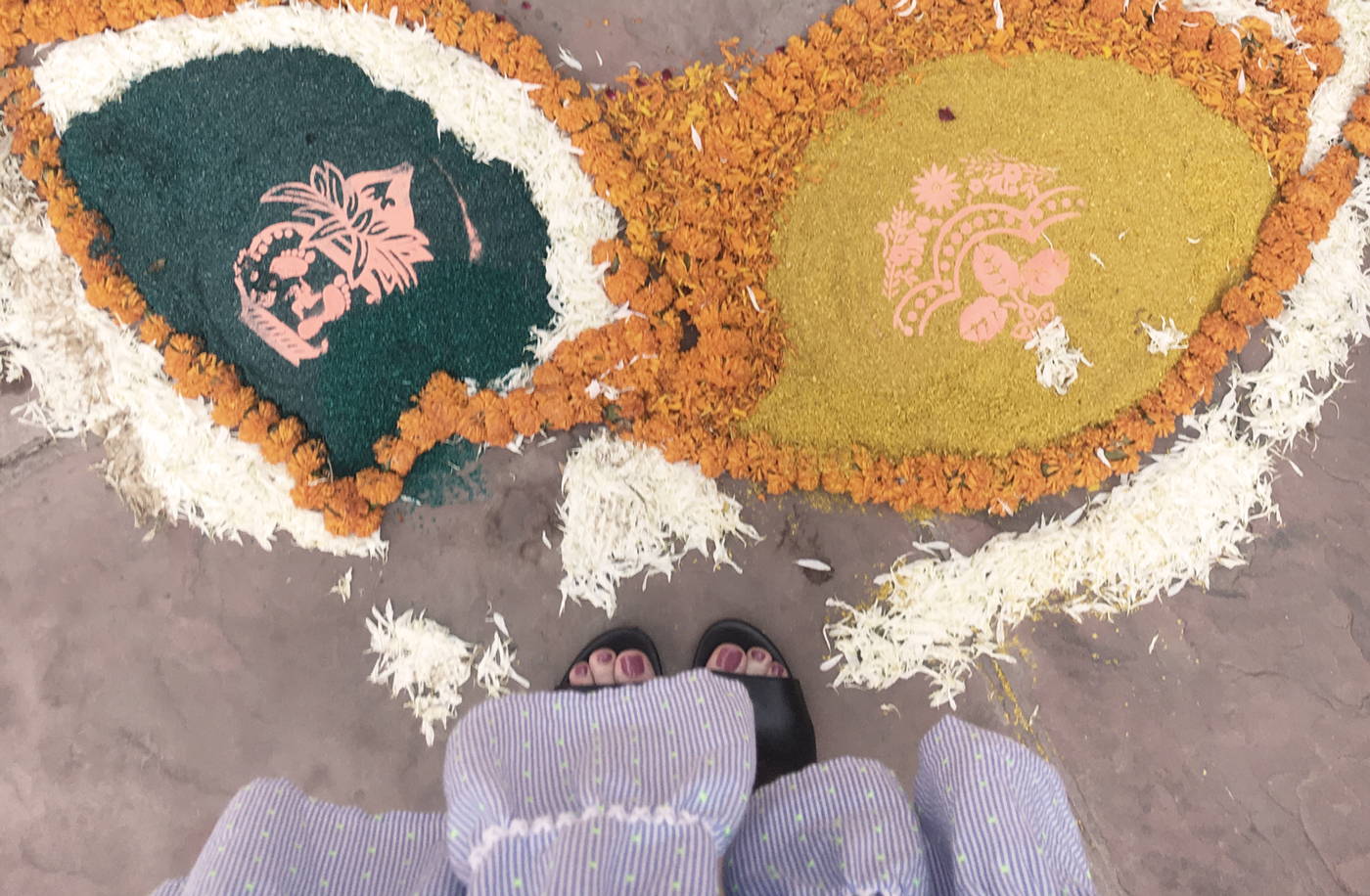 Girl standing next to a colorful flower arrangement in India.