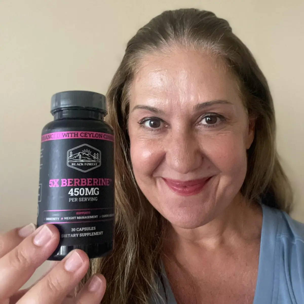 A smiling woman holding a berberine bottle