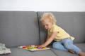 Kid playing on a sofa with a Montessori toy