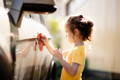 Little girl cleaning the car. 