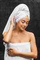 woman with a towel on her head smiling after cleansing her face