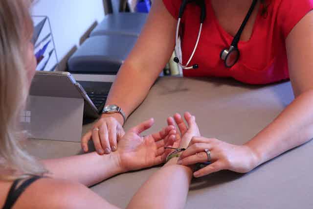 Dr. Keila Roesner in consultation with a female client, checking her pulse