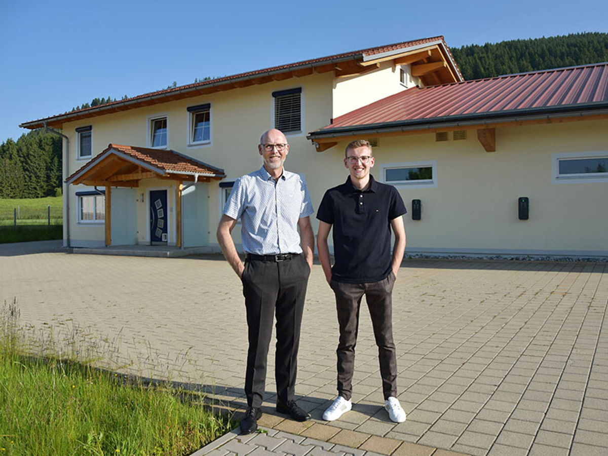 Jürgen und Dominik Weiher stehen vor einem gelben Haus