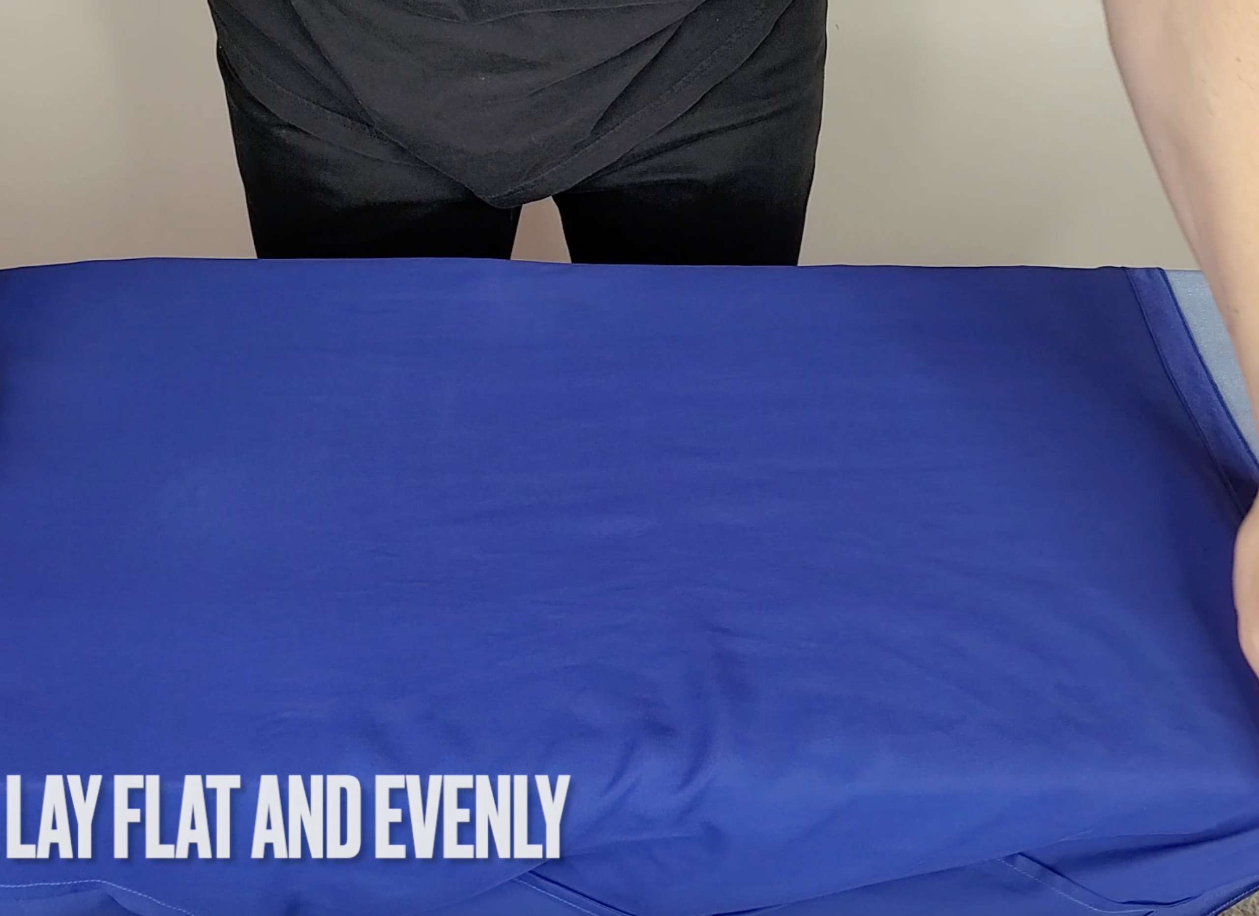photo of a man laying a silk pajama shirt flat and evenly on an ironing board