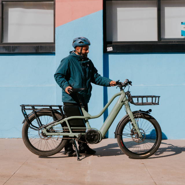 a man standing next to a green Momentum PakYak E+ electric cargo bike