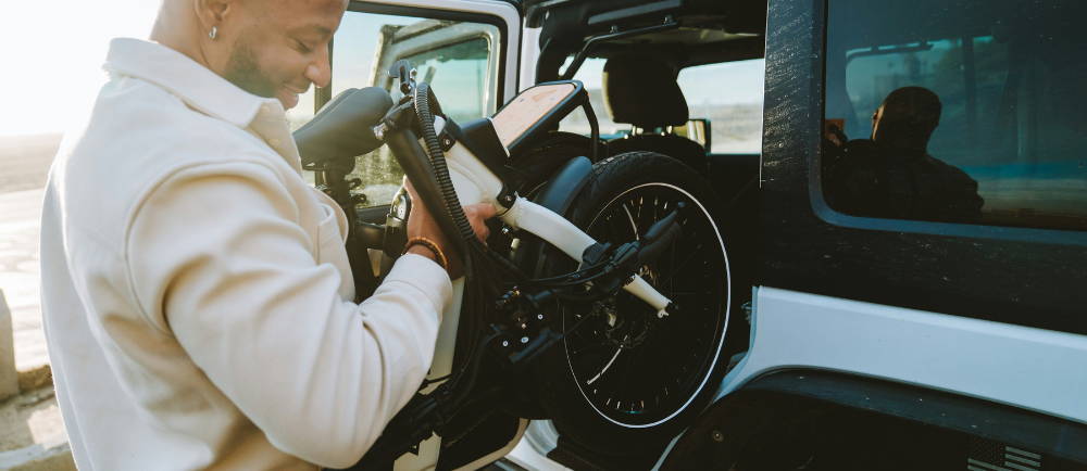 Man lifting folding electric bike into car