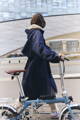 Femme habillée en trench-coat avec son vélo de ville
