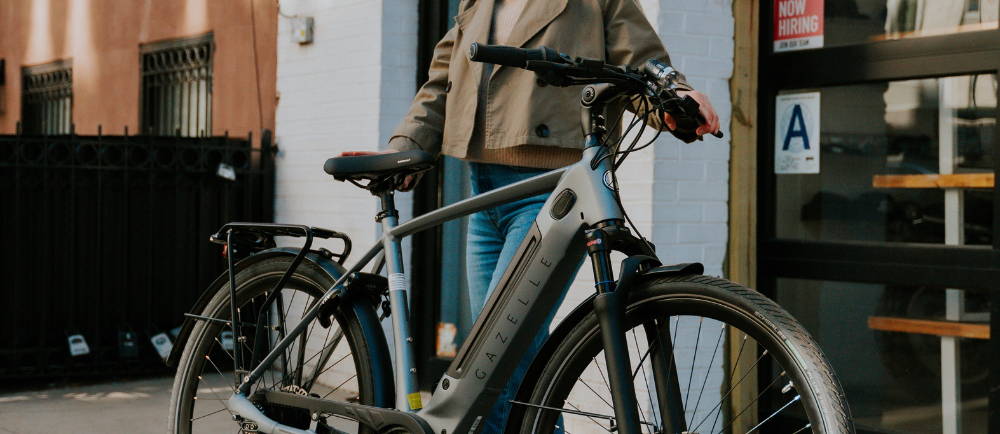 a woman standing next to a Gazelle Ultimate C380+ electric city bike