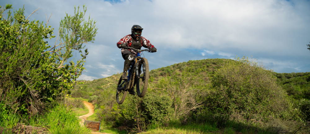 An e-MTB rider on a trail doing a jump