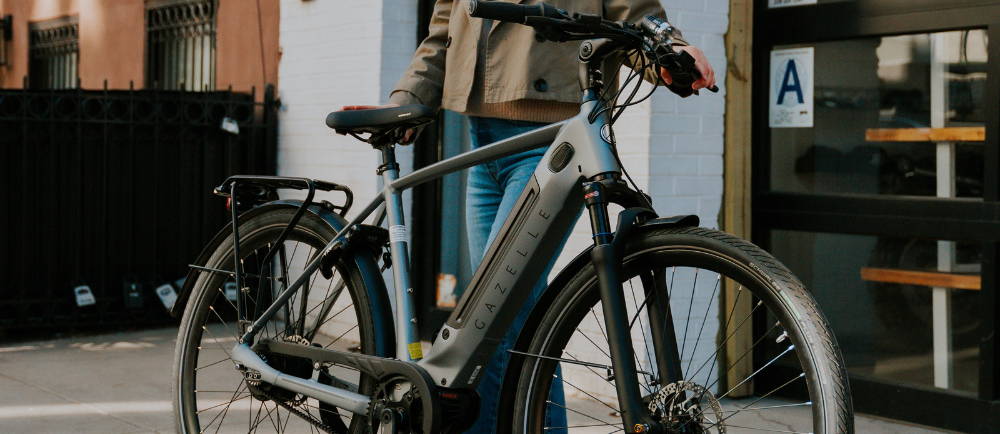 Woman with Gazelle electric bike on sidewalk