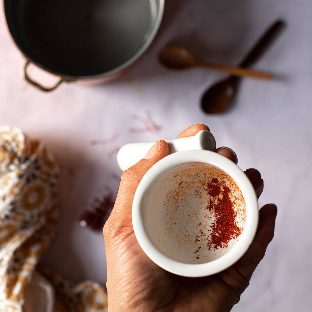 A white mortar and pestle is filled with a small amount of ground saffron