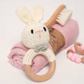 Cute bunny crochet toy for babies, with a brush, blanket, and a pacifier in the background. 