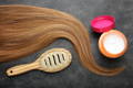 Hair tresses with comb and deep treatment hair mask against grey background