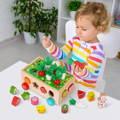 Cute toddler playing with the Montessori Carrot Wheels toy and holding a worm and a red carrot in her hands.