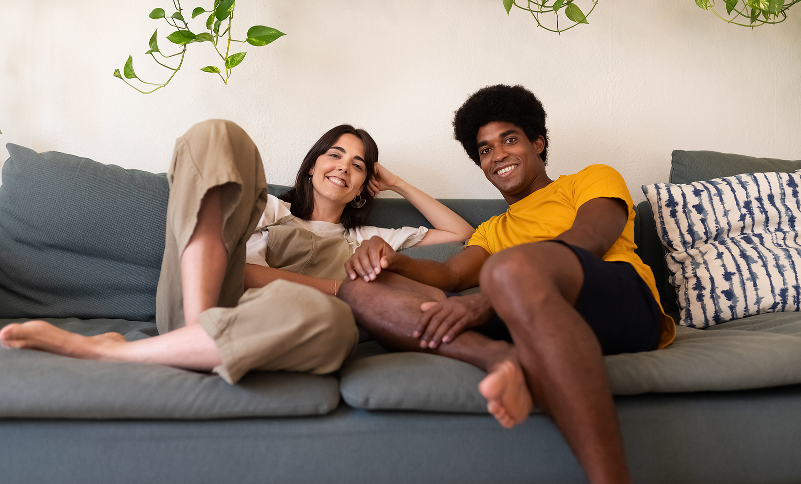 Smiling young interracial couple relaxing on the couch looking at camera.